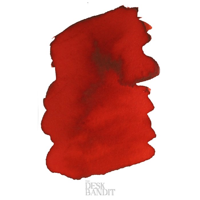 Rubine - 2ml ink sample by Robert Oster, featuring a vivid red pigment blotch on a white background, with a faint THE DESK BANDIT watermark.