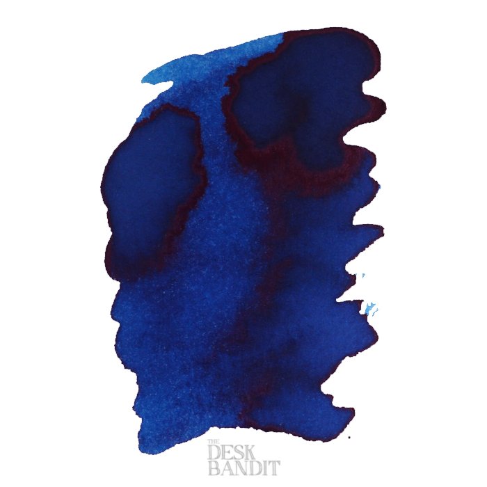 Abstract ink swatch of Robert Oster's School Blue - 50ml, showcasing deep blue hues with a red-purple sheen, featuring THE DESK BANDIT watermark.