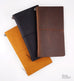 Leather Cover (Brown) for travelers' notebooks, made of soft leather, shown closed with an elastic band, featuring The Desk Bandit logo on a light background.