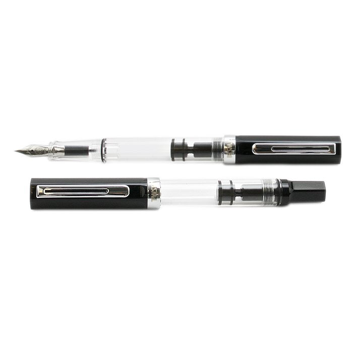 ECO (Black) - Medium fountain pen, demonstrator style, with one cap removed showing the nib and clear barrel displaying the piston-filling mechanism; another pen is capped.