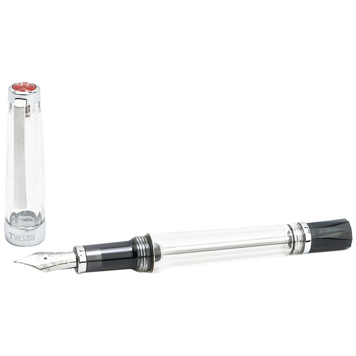 VAC 700R (Clear) - Broad fountain pen with a transparent barrel, visible piston mechanism, metal nib, and detached cap marked “TWSBI”, showcasing its vacuum filling system.