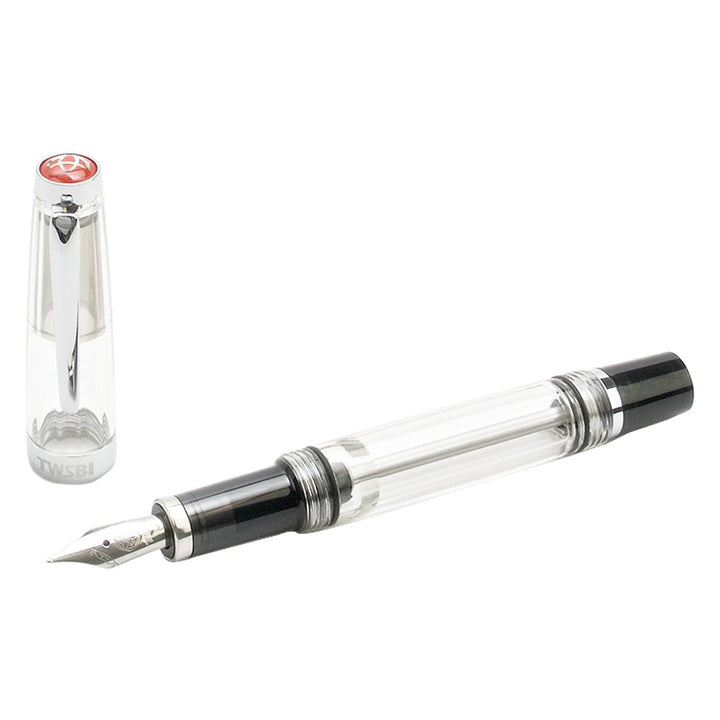 VAC Mini (Smoke) - Medium fountain pen with clear barrel, silver nib, black feed, and transparent cap featuring a metal clip and colored logo.