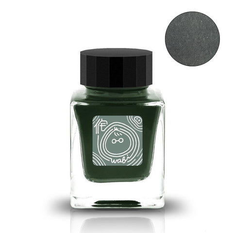 Small square glass bottle of Wabi 侘 - 2ml ink sample by Tono & Lims, featuring a black cap and decorative label, showcasing the ink's deep forest-green shade.