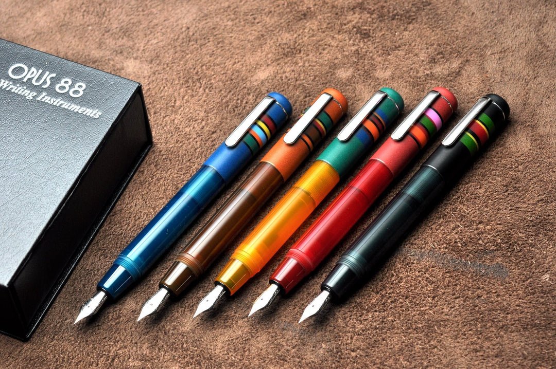 Opus 88 Fantasia - Green (Fine) fountain pen with matching cap, silver clip, colorful bands, and presentation box on suede surface. Includes eyedropper tool and JoWo nib.